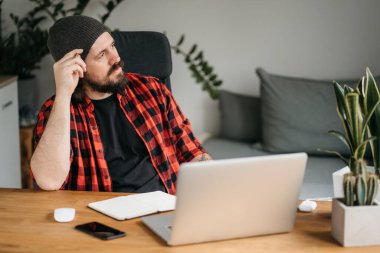Focused handsome young man is studying online, watching online webinar, video classes on the laptop. Man e-studying, doing researching sitting at home. High quality photo