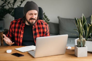 Young man is a freelancer in casual clothing, he concentrates on a laptop in a cafe. A stylish young man looks at the laptop screen with amazement. Work on a laptop in a cafe. High quality photo