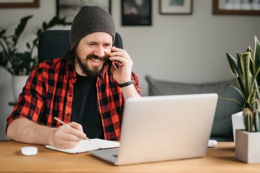 Man taking notes down from his new laptop computer at work in the morning office with coffee. High quality photo