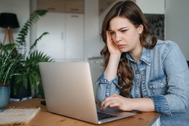 Sad woman looking annoyed and stressed, sitting at the desk, using a laptop, thinking, feeling tired and bored with depression problems. High quality photo