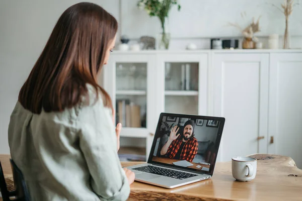 Video call, video meeting. A young woman is discussing some business tasks with a young man via video, she sits at office space and looks at webcam