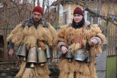 Breznik, Bulgaria - January 21, 2023: Unidentified people with traditional Kukeri costume are seen at the Festival of the Masquerade Games Surova in Breznik, Bulgaria