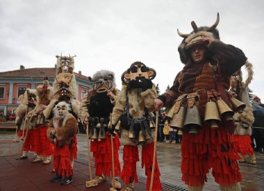 Breznik, Bulgaria - January 21, 2023: Unidentified people with traditional Kukeri costume are seen at the Festival of the Masquerade Games Surova in Breznik, Bulgaria