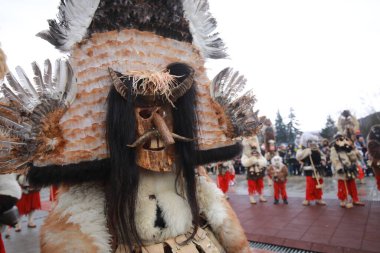Breznik, Bulgaria - January 21, 2023: Unidentified people with traditional Kukeri costume are seen at the Festival of the Masquerade Games Surova in Breznik, Bulgaria