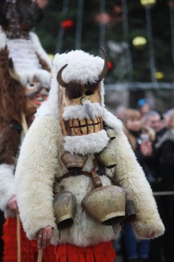 Breznik, Bulgaria - January 21, 2023: Unidentified people with traditional Kukeri costume are seen at the Festival of the Masquerade Games Surova in Breznik, Bulgaria