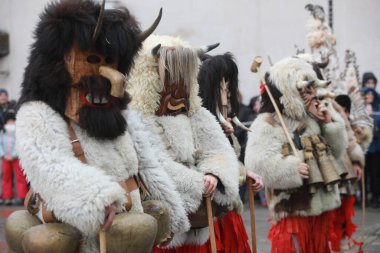 Breznik, Bulgaria - January 21, 2023: Unidentified people with traditional Kukeri costume are seen at the Festival of the Masquerade Games Surova in Breznik, Bulgaria