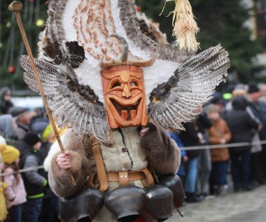 Breznik, Bulgaria - January 21, 2023: Unidentified people with traditional Kukeri costume are seen at the Festival of the Masquerade Games Surova in Breznik, Bulgaria