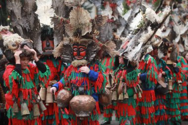 Breznik, Bulgaria - January 21, 2023: Unidentified people with traditional Kukeri costume are seen at the Festival of the Masquerade Games Surova in Breznik, Bulgaria