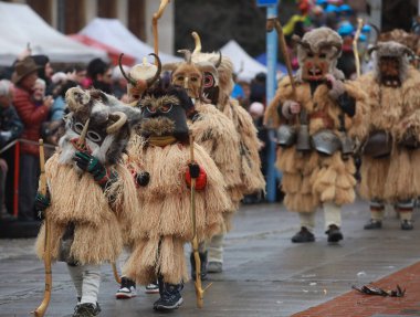 Breznik, Bulgaria - January 21, 2023: Unidentified people with traditional Kukeri costume are seen at the Festival of the Masquerade Games Surova in Breznik, Bulgaria