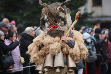 Breznik, Bulgaria - January 21, 2023: Unidentified people with traditional Kukeri costume are seen at the Festival of the Masquerade Games Surova in Breznik, Bulgaria