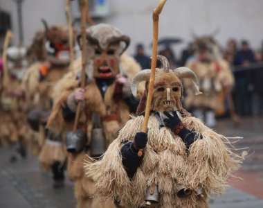 Breznik, Bulgaria - January 21, 2023: Unidentified people with traditional Kukeri costume are seen at the Festival of the Masquerade Games Surova in Breznik, Bulgaria