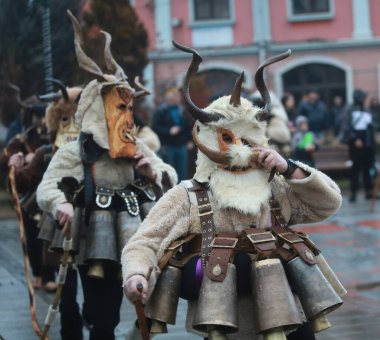 Breznik, Bulgaria - January 21, 2023: Unidentified people with traditional Kukeri costume are seen at the Festival of the Masquerade Games Surova in Breznik, Bulgaria