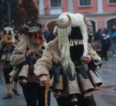 Breznik, Bulgaria - January 21, 2023: Unidentified people with traditional Kukeri costume are seen at the Festival of the Masquerade Games Surova in Breznik, Bulgaria
