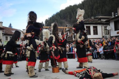 Shiroka laka, Bulgaristan - 5 Mart 2023: Bulgaristan 'ın Shiroka laka kentinde düzenlenen Maskeli Balo Festivali' nde maskeli insanlar dans ediyor ve kötü ruhları korkutmak için gösteri yapıyorlar..