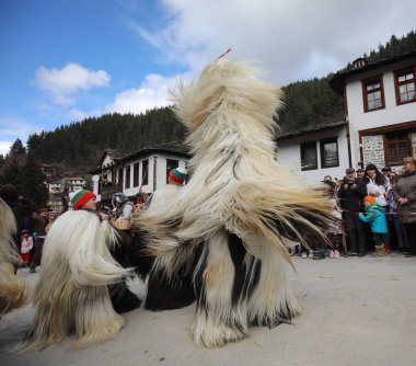 Shiroka laka, Bulgaristan - 5 Mart 2023: Bulgaristan 'ın Shiroka laka kentinde düzenlenen Maskeli Balo Festivali' nde maskeli insanlar dans ediyor ve kötü ruhları korkutmak için gösteri yapıyorlar..