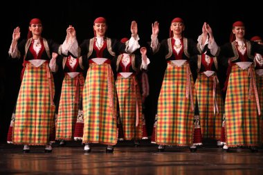 Sofya, Bulgaristan - 11 Mart 2023: Geleneksel folklor kostümlü insanlar Bulgaristan 'ın Sofya kentindeki Ulusal Folklor Meclisi' nde halk dansı yaptılar
