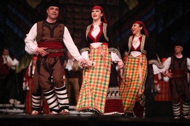 Sofya, Bulgaristan - 11 Mart 2023: Geleneksel folklor kostümlü insanlar Bulgaristan 'ın Sofya kentindeki Ulusal Folklor Meclisi' nde halk dansı yaptılar