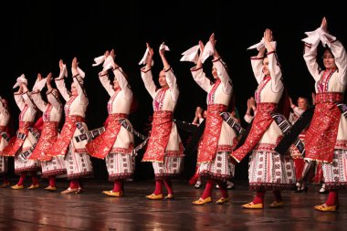 Sofya, Bulgaristan - 11 Mart 2023: Geleneksel folklor kostümlü insanlar Bulgaristan 'ın Sofya kentindeki Ulusal Folklor Meclisi' nde halk dansı yaptılar