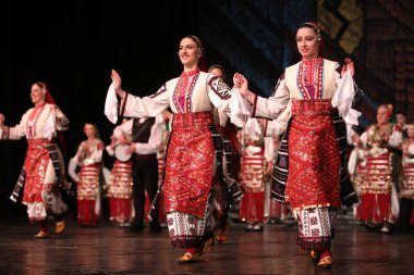 Sofya, Bulgaristan - 11 Mart 2023: Geleneksel folklor kostümlü insanlar Bulgaristan 'ın Sofya kentindeki Ulusal Folklor Meclisi' nde halk dansı yaptılar