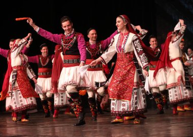 Sofya, Bulgaristan - 11 Mart 2023: Geleneksel folklor kostümlü insanlar Bulgaristan 'ın Sofya kentindeki Ulusal Folklor Meclisi' nde halk dansı yaptılar