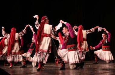 Sofya, Bulgaristan - 11 Mart 2023: Geleneksel folklor kostümlü insanlar Bulgaristan 'ın Sofya kentindeki Ulusal Folklor Meclisi' nde halk dansı yaptılar