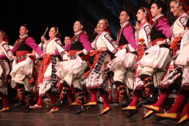 Sofya, Bulgaristan - 11 Mart 2023: Geleneksel folklor kostümlü insanlar Bulgaristan 'ın Sofya kentindeki Ulusal Folklor Meclisi' nde halk dansı yaptılar