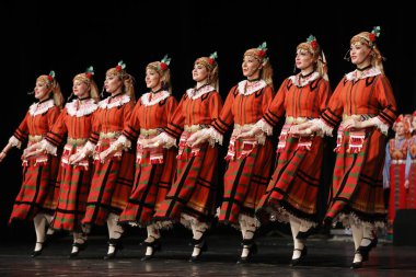 Sofya, Bulgaristan - 11 Mart 2023: Geleneksel folklor kostümlü insanlar Bulgaristan 'ın Sofya kentindeki Ulusal Folklor Meclisi' nde halk dansı yaptılar