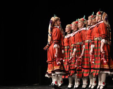 Sofya, Bulgaristan - 11 Mart 2023: Geleneksel folklor kostümlü insanlar Bulgaristan 'ın Sofya kentindeki Ulusal Folklor Meclisi' nde halk dansı yaptılar