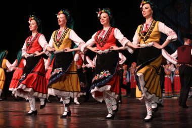 Sofya, Bulgaristan - 11 Mart 2023: Geleneksel folklor kostümlü insanlar Bulgaristan 'ın Sofya kentindeki Ulusal Folklor Meclisi' nde halk dansı yaptılar