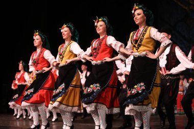 Sofya, Bulgaristan - 11 Mart 2023: Geleneksel folklor kostümlü insanlar Bulgaristan 'ın Sofya kentindeki Ulusal Folklor Meclisi' nde halk dansı yaptılar