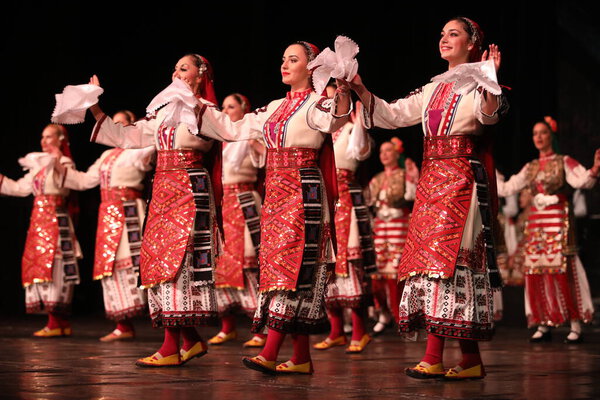 Sofia, Bulgaria - March 11, 2023: People in traditional folk costumes perform a folk dance at the National Folklore Assembly in Sofia, Bulgaria