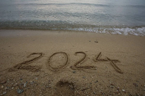 新しい2024年 波と澄んだ青い海でビーチにレタリング 海岸の数 2024 美しいビーチの背景に黄金の砂に手書きされたメッセージ 新年コンセプト ストック写真