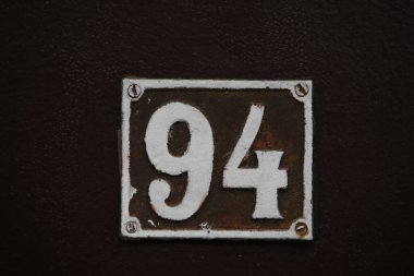Vintage square ceramic street number plate with number. Close up, brand.
