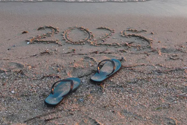 stock image New Year 2025, lettering on the beach. Numbers 2025 year on the sea shore, message handwritten in the golden sand on beautiful beach background. New Years concept.