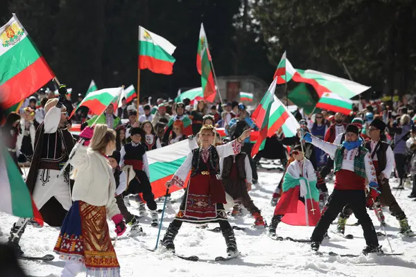 stock image Pamporovo, Bulgaria - March 03, 2024 - Skiing with Bulgarian flags at Pamporovo ski resort, Bulgaria. People dressed with traditional Bulgarian clothes celebrated by ski parade with the Bulgarian flag downhill the Snezhanka peak