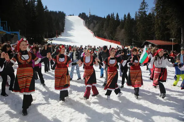 stock image Pamporovo, Bulgaria - March 03, 2024 - Skiing with Bulgarian flags at Pamporovo ski resort, Bulgaria. People dressed with traditional Bulgarian clothes celebrated by ski parade with the Bulgarian flag downhill the Snezhanka peak
