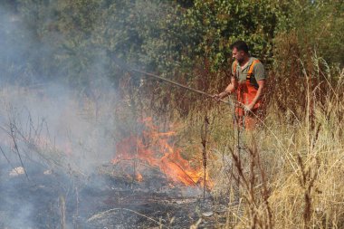 Sofya, Bulgaristan - 13 Ağustos 2024: İtfaiyeciler Bulgaristan 'ın Sofya Havaalanı yakınlarındaki bir sahada kuru çimen yakmaktan çıkan yangını söndürdüler