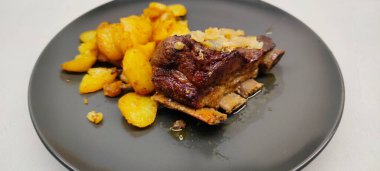 Koyu bir tabakta kızarmış dana pirzolası ve kızarmış patatesi yakından görmek.