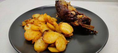   Kızarmış dana pirzolası ve kızarmış patatesi siyah tabakta görmek.