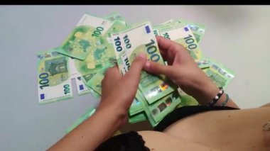 İç çamaşırlı bir kadın 100 Euro 'luk banknotlar sayıyor, göğüsler sütyende, üst manzara