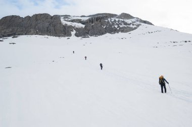 Snow hikers climbing a snowy mountain e in a sunny day in Ordesa Natural Park, Pyrenees Spain