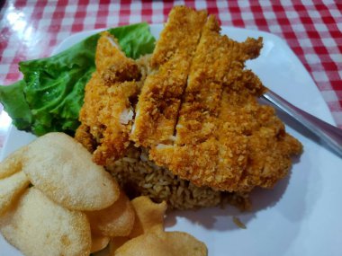 Kızarmış pirinç ve beyaz tabakta tavuk katsu.