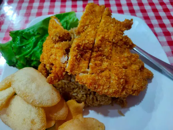 Kızarmış pirinç ve beyaz tabakta tavuk katsu.