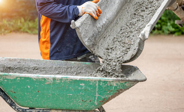 Обслуживание бетоносмесительных грузовиков, заливающих цемент в строительство участка в дневное время. Цемент был налит в инвалидное кресло или цементную тележку, чтобы сделать пол