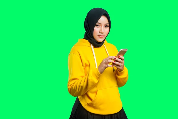 美しいアジア系のイスラム教徒の女の子の笑顔と携帯電話を持ち — ストック写真