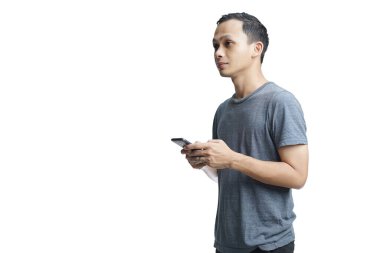 Gülümseyen yakışıklı Asyalı sıradan giyinmiş cep telefonuyla izole edilmiş stüdyo arka planı kullanıyor.