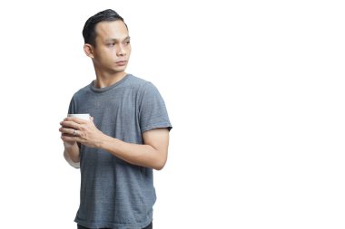 Yakışıklı Asyalı adam arka planda bir fincan kahve tutuyor.