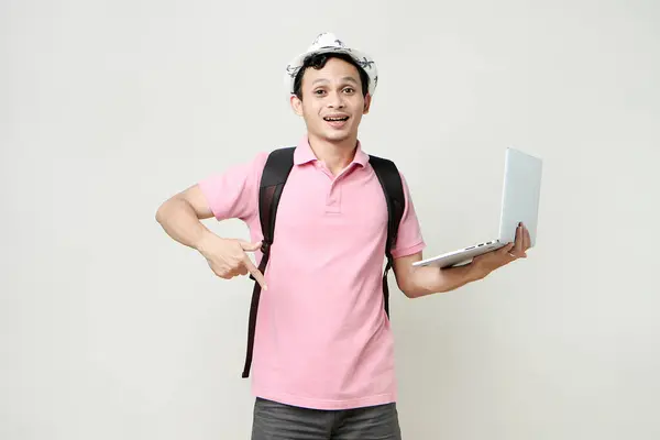 Asian man backpacker holding laptop computer with pointing finger gesture. digital nomad and travelling concept. on isolated background