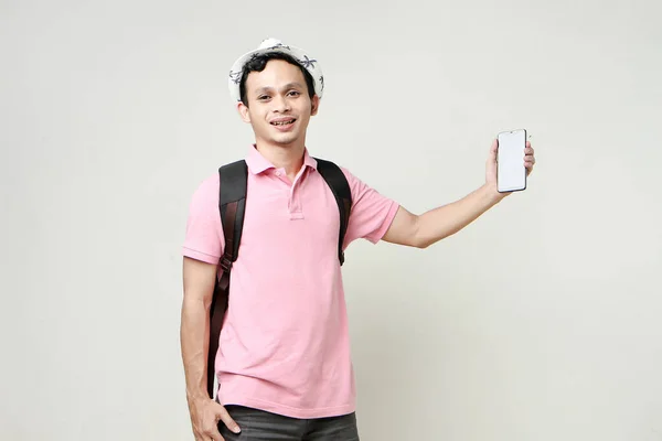 Asian man backpacker showing cellphone blank screen with empty space for mobile app on screen. travelling concept. on isolated background