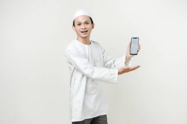 Mutlu Asyalı Müslüman boş telefon ekranı gösteriyor. İnsanlar dini İslam yaşam tarzı kavramını benimsiyor. Ramazan ve Mübarek bayramını kutluyoruz. izole edilmiş arka grupta